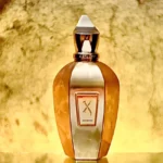 بطری عطر زرجف اکسنتو با بدنه تراش‌خورده طلایی و پلاک برجسته در پس‌زمینه طلایی.