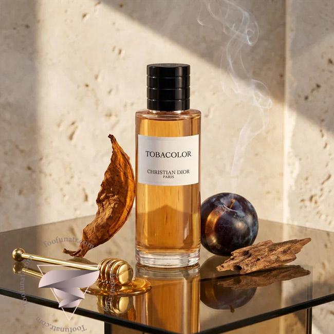شیشه عطر دیور توباکالر روی میز براق کنار برگ خشک تنباکو آلو عسل و دود