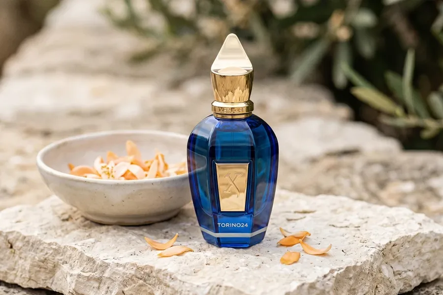 شیشه عطر آبی زرجف تورینو 24 روی سنگ کنار کاسه حاوی گلبرگها