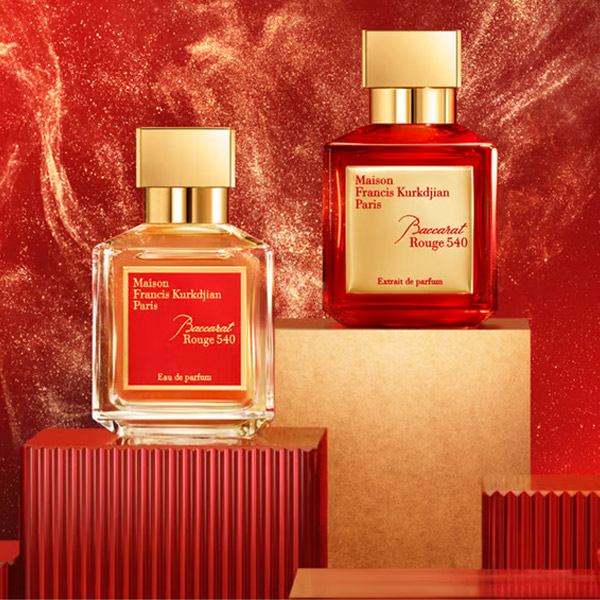 دو شیشه عطر Baccarat Rouge 540 در پس زمینه قرمز لوکس با ذرات طلایی درخشان