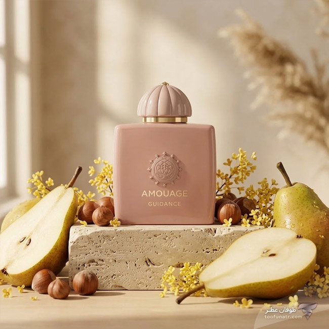 شیشه عطر آمواژ گایدنس در کنار گلابی نصف شده و فندق روی سنگ تراورتن.