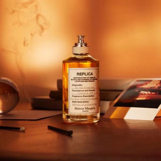 شیشه عطر میسون مارژیلا رپلیکا بای د فایر پلیس روی میز چوبی با نور گرم