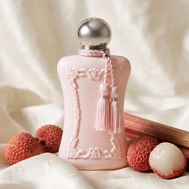 عطر زنانه پارفومز د مارلی دلینا صورتی روی پارچه کرم در کنار میوههای سرخالو و ریواس