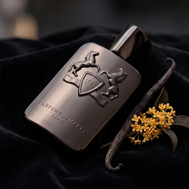 شیشه عطر تیره پارفومز د مارلی روی مخمل مشکی کنار چوب وانیل و گلهای زرد